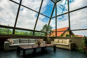 une grande chambre avec une table et des canapés devant les fenêtres dans l'établissement Hotel Sunny Hill, à Cluj-Napoca