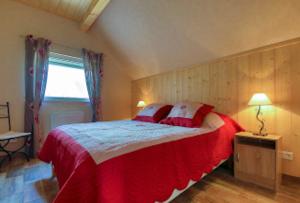 Schlafzimmer mit einem großen Bett mit roter und weißer Bettwäsche in der Unterkunft Gite au pré des Oies in Ostheim