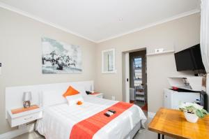 a white bedroom with a bed and a table at King Guest Lodge in Port Elizabeth