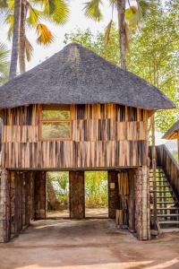 a bamboo hut with a thatched roof and palm trees at Epupa Falls Lodge in Epupa +24 photos