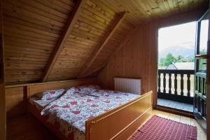 un letto in una camera in legno con una grande finestra di Cottage Walnut a Kolašin