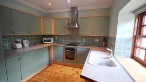 una cocina con armarios azules y fregadero en Smiddy Lodge, en Balloch