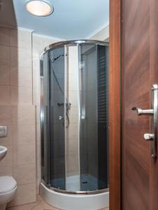 W łazience znajduje się prysznic ze szklanymi drzwiami. w obiekcie Prima w mieście Puławy