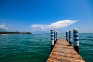 un quai dans l'eau avec des poteaux bleus et blancs dans l'établissement Apparthotel San Sivino, à Manerba del Garda