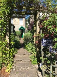 a stone pathway leading to a house with a sign at Harvel Cottage in Paulton