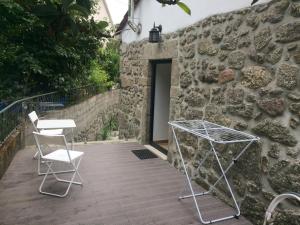 a patio with two chairs and a table in front of a stone wall at Outeiro House in Ponte de Lima