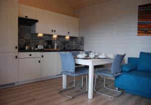 a kitchen with a white table and blue chairs at Uzenabow in Wicie