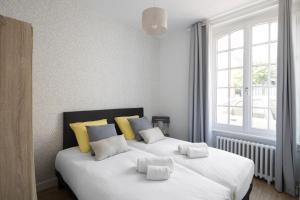 a bedroom with a large white bed with yellow pillows at Le Safran by Cocoonr in Dinard