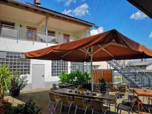 eine Terrasse mit einem Sonnenschirm, Tischen und Stühlen in der Unterkunft Gasthaus zum Löwen in Seckach