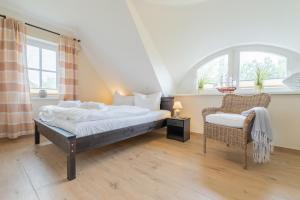 1 dormitorio con 1 cama, 1 silla y 1 ventana en Reetdachhäuser Börgerende, en Börgerende-Rethwisch