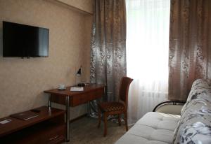 a hotel room with a bed and a desk and a television at Avtozavodskaya Hotel in Nizhny Novgorod