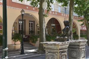 a statue of a girl sitting on a fountain in a street at Logis Hôtel Restaurant Grand Hôtel de Lyon in Vals-les-Bains