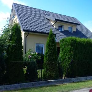 a house with a black roof and some bushes at Wczasy u Ireny in Lubiatowo