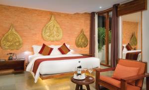 um quarto com uma cama grande e uma cadeira em Golden Temple Residence em Siem Reap