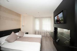 a bedroom with a bed and a flat screen tv at NOX Kensington in London