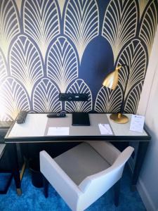 a desk with a lamp and a chair in front of a wall at Best Western Hôtel Journel Paris Sud in Ris-Orangis