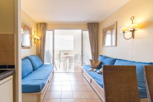 uma sala de estar com um sofá azul e uma mesa em Résidence Pierre & Vacances Les Restanques du Golfe de Saint-Tropez em Grimaud