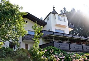 Biały dom z czarnym balkonem i kwiatami w obiekcie Aparthotel Pan Haus w mieście Bad Ischl