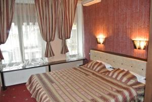 a bedroom with a bed and two windows with curtains at Annabelle отель in Odesa