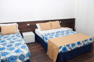 a bedroom with two beds with blue and white sheets at Casa Restino in Torre del Greco