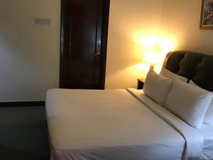 een hotelkamer met een wit bed en een lamp bij KL Service Suites at Times Square KL in Kuala Lumpur