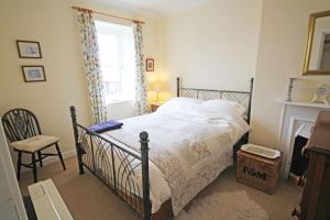 a bedroom with a bed and a chair and a fireplace at Sunnieside Cottage in Seahouses