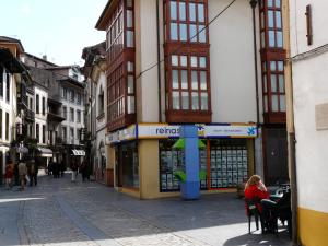 a street with people sitting in chairs in front of a store at Sol 23 in Villaviciosa