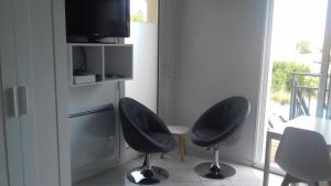 レ・サ​​ーブル・ドロンヌにあるLa Chaumetteの椅子2脚、テーブル、テレビが備わる客室です。