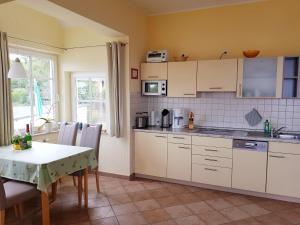a kitchen with white cabinets and a table and a table and chairs at Über dem Meer in Lohme
