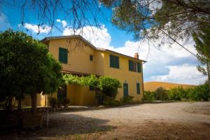 a yellow house with green shutters on it at La Nostra Maremma in Marsiliana