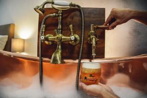 une personne détient un verre de bière dans une baignoire dans l'établissement U Medvidku-Brewery Hotel, à Prague