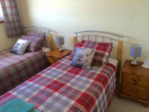 a bedroom with two beds and two lamps on tables at Inverkenny House in Inverness