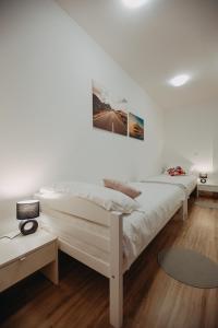 two white beds in a room with wooden floors at Apartman Vejama in Josipdol
