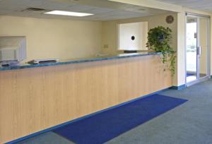 an empty office lobby with a counter with a plant at America's Inn - Leeds in Leeds