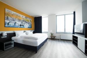 a bedroom with a bed and a flat screen tv at Carathotel Düsseldorf City in Düsseldorf