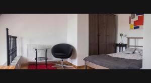 a bedroom with a black chair and a bed at Apartament Serce Miasta | The Heart of the City in Suwałki