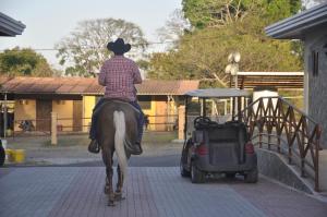 a man riding a horse next to a golf cart at Pocri Country Resort in Aguadulce