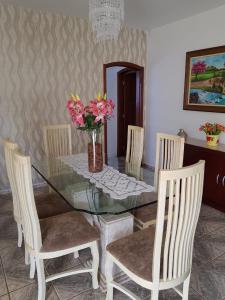a glass dining room table with chairs and a vase of flowers at Recanto Dos Gansos in Pardinho