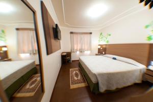 Habitación de hotel con 2 camas y espejo en Hotel Premium Pirassununga, en Pirassununga