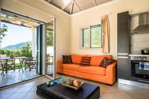 Aktes villas في فاسيليكي: غرفة معيشة مع أريكة برتقالية وطاولة