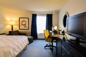 a hotel room with a bed and a flat screen tv at Heritage Inn & Suites Ridgecrest - China Lake in Ridgecrest