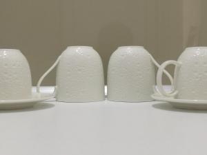 three white cups and saucers on a white table at Afytos Dream suites sea view in Afitos