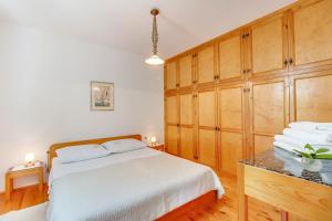 sypialnia z białym łóżkiem i drewnianymi szafkami w obiekcie Apartman Pia w miejscowości Mali Lošinj