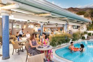 a group of people sitting around a pool at a restaurant at Sorriso Thermae Resort & Spa in Ischia