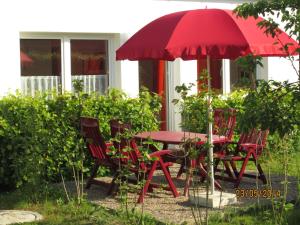 una mesa roja y sillas con una sombrilla roja en Ferienhaus Am Peenestrom en Quilitz