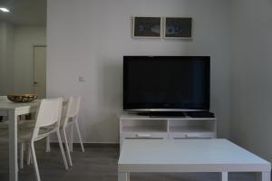 sala de estar con TV y mesa con sillas en BOREAS Apartaments en Palamós