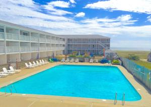 a pool at a hotel with chairs and a building at Sandcastle Resort in Provincetown