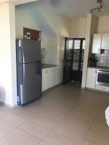 eine Küche mit einem Kühlschrank aus Edelstahl und weißen Schränken in der Unterkunft Limni Pool House B in Larnaka