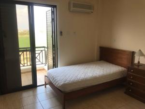 a bedroom with a bed and a door to a balcony at Limni Pool House B in Larnaca