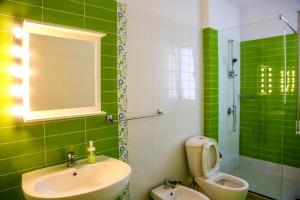 a green bathroom with a sink and a toilet at Claudine Apartment in Durrës
